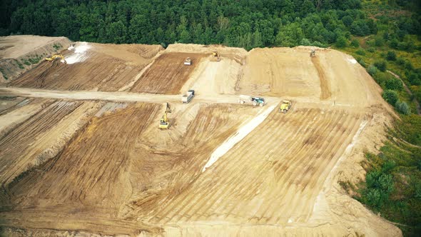 Aerial top down view of an excavator loading crushed stone into a dump truck in a crushed stone quar