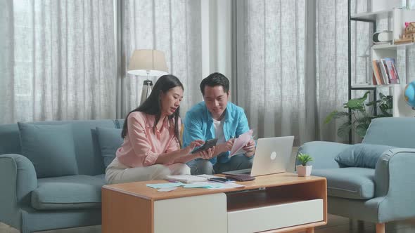 Asian Couple With A Laptop Helping Each Other Calculating Money By Calculator