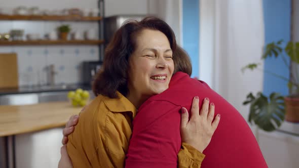 Happy Smiling Senior Mother with Adult Son Hugging at Home