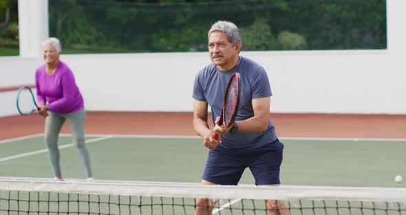 Video of happy biracial senior couple during training on tennis court