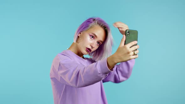 Trendy Mannered Girl Making Selfie on Smartphone Over Blue Background. Woman with Dyed Violet