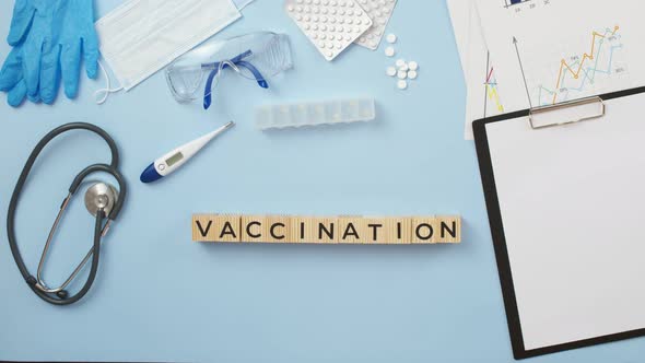 Word the vaccination is collected by a doctor from wooden cubes on medical table, a view from above.