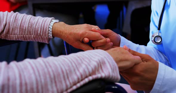 Mid section of female doctor consoling sad disabled senior woman at nursing home 4k