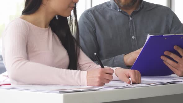 Cropped Shot of a Woman Signing Papers with the Salesman at the Car Salon