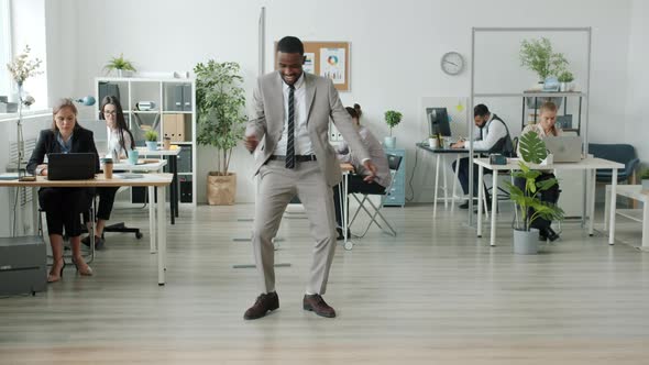 AfroAmerican Performer Dancing in Modern Office While People in Suits Working in Background