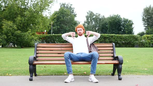 Both Hands Thumbs Down by Man Sitting on Bench in Park