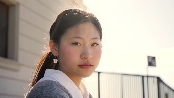 Outdoor Portrait of a Chinese Woman Looking at the Camera with a Serious Face and Intense Look
