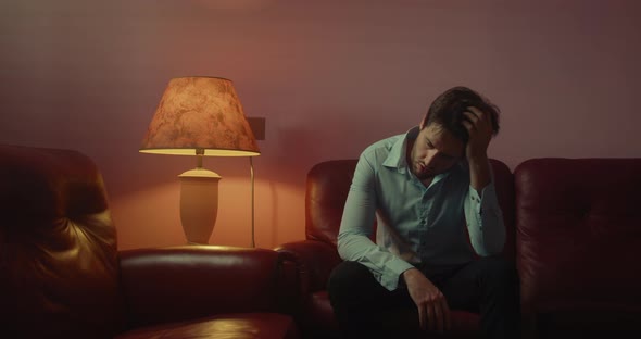 Desperate man sitting on the red sofa at home