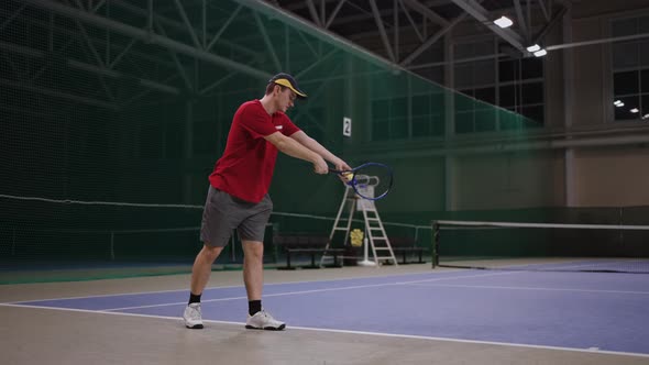 Beginning Tennis Player is Learning to Serve Fulllength Portrait on Indoor Tennis Court Training and