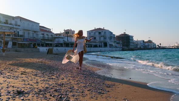 Woman Wearing Straw Hat and White Dress on Shoreline at Spetses Greece