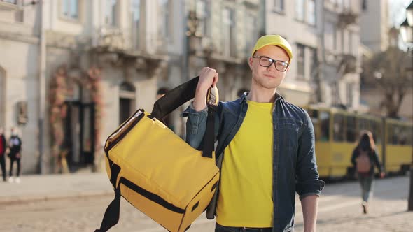 Portrait of a Young Delivery Man Who is Standing and He Throws His Backpack Over His Shoulder