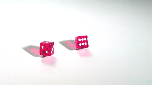 Pink dice rolling on white surface