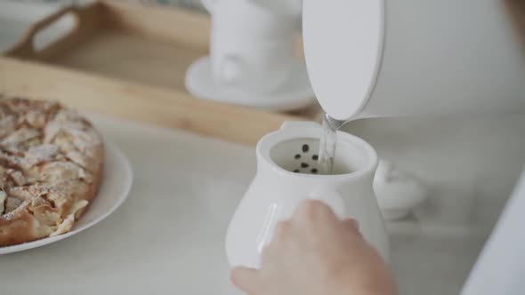 Closeup of Boiling Water From White Kettle Being Poured Into Teapot