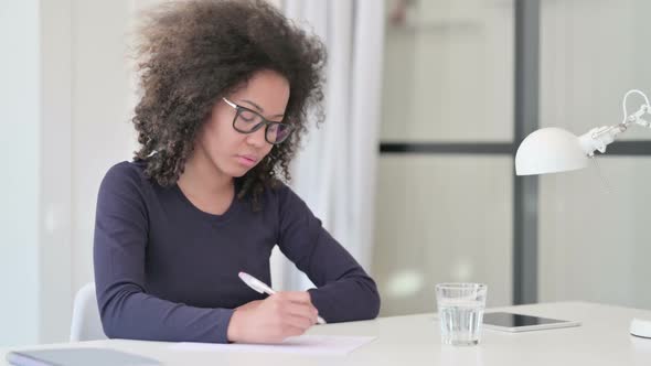 African Woman Writing on Paper at Work