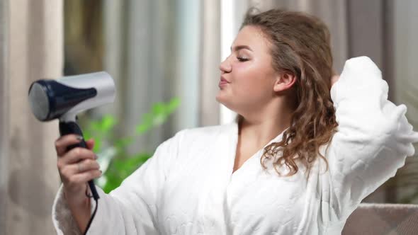 Side View Portrait of Charming Confident Plussize Woman Drying Hair with Hair Dryer at Home in the