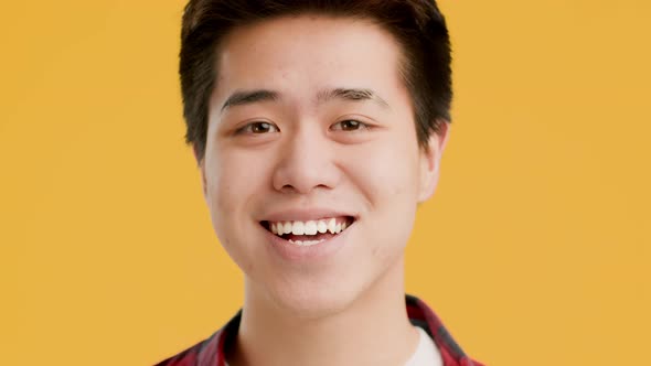 Korean Guy Smiling Raising Eyebrows Looking At Camera Yellow Background
