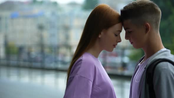 Young Couple Looking Each Other on Rain City Background Touching Foreheads