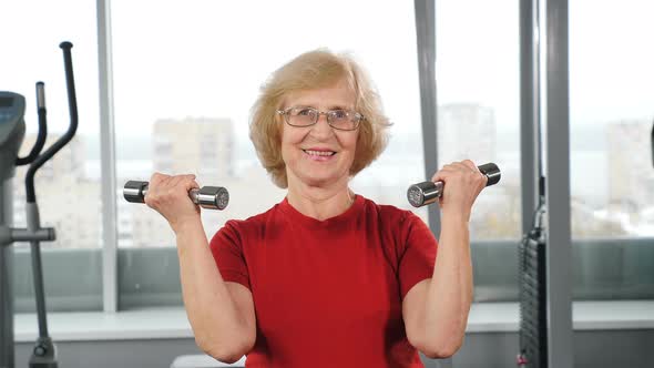 Old Positive Woman in Gym Lifting Barbells