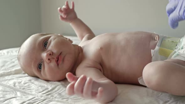 Neonatologist in Latex Gloves Examines a Newborn Baby with a Stethoscope. Close-up.