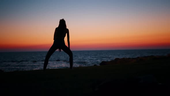 Silhouette of Woman Stretching Legs After Workout on Beach