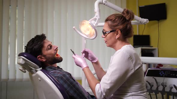 Woman Dentist Examining Patient's Teeth in Clinic