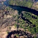 Aerial view of the river between the pines. Flying over a winding riverbed surrounded by treetops - VideoHive Item for Sale