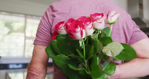 Caucasian senior man giving a flower bouquet to his wife at home