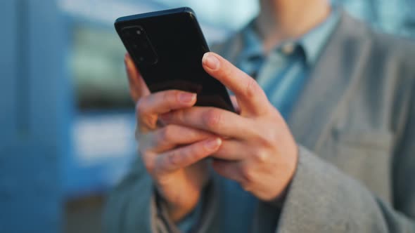 Woman in a Coat Walking Around the City in the Early Morning and Using Smartphone