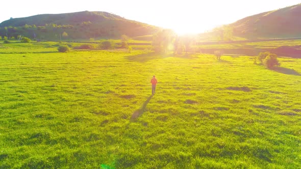 Flight Over Sport Man at Perfect Green Grass Meadow. Sunset in Mountain