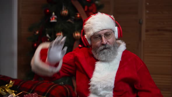 Portrait of Santa Claus Dancing Funny in Big Red Headphones