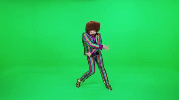 A Retro Dude in a Multicolored Suit is Dancing a Funny Dance on a Green Background a Festive Mood a