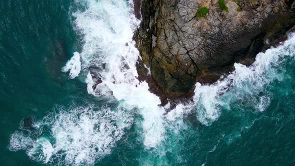 Aerial view Andaman Sea coast, huge seas crashing into the shores filled with black Mountain rocks