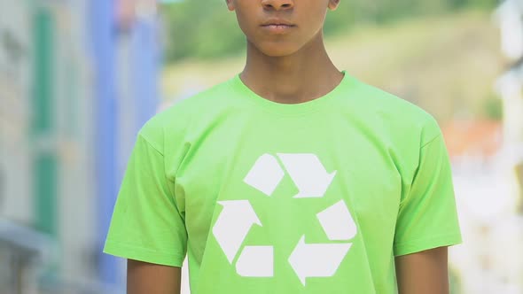 Serious boy in shirt with recycle sign promoting reusable products