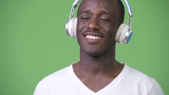 Young African Man Listening To Music Against Green Background