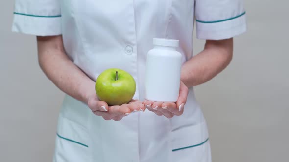 Nutritionist Doctor Healthy Lifestyle Concept - Holding Organic Green Apple and Jar of Vitamin Pills