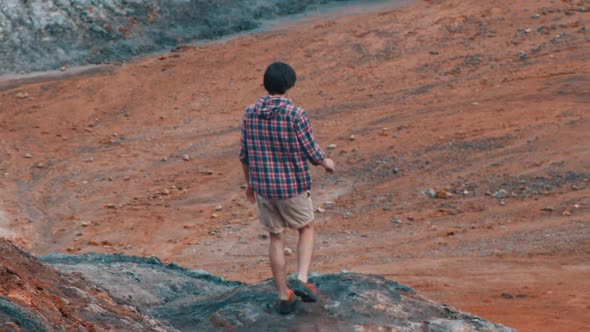 Young Man Traveler Walking on an Orange Clay Mountains