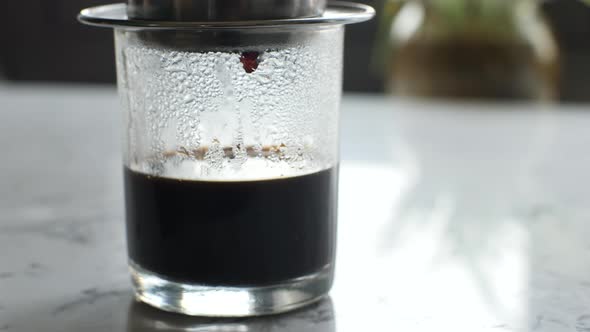 CloseUp Of A Transparent Glass Standing on The Table Dripping Coffee Drop By Drop