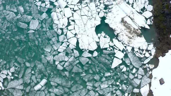 Aerial top of view of turquoise lake full of different shapes and sizes ice rafts and blocks, filmed