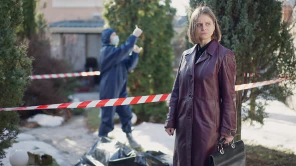 Portrait of Serious Thoughtful Female Detective Standing at Warning Tape at Crime Scene Looking