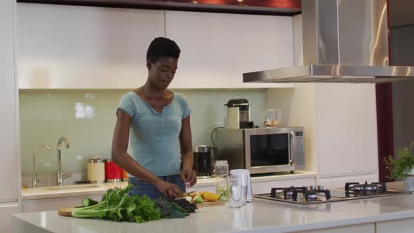 African american attractive woman chopping vegetables for smoothie in kitchen