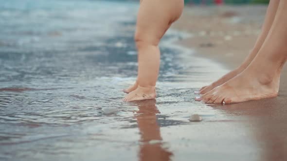 Mother and Baby Foot Walking on Sand Beach. Newborn Kid Feet at Beach