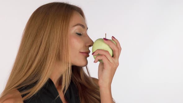 Attractive Young Woman Smelling Delicious Green Apple, Smiling Cheerfully