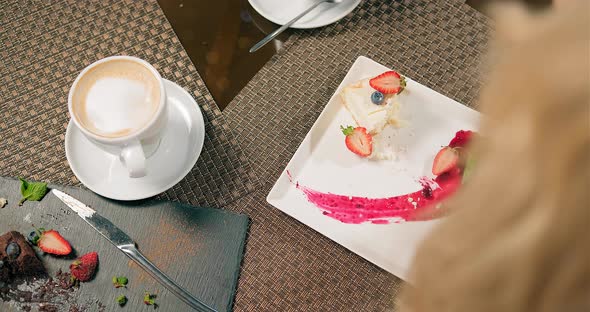 Woman Eats Cheesecake with Fresh Strawberries in Restaurant