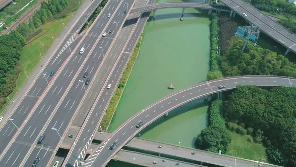 Aerial Tilt View of a Highway Overpass Multilevel Junction with Fast Moving Cars Surrounded By Green