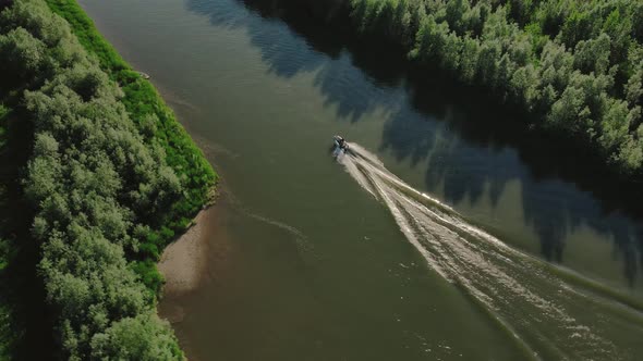 A small motorboat driving through a small cut surrounded by beautiful scenery in the middle of a den