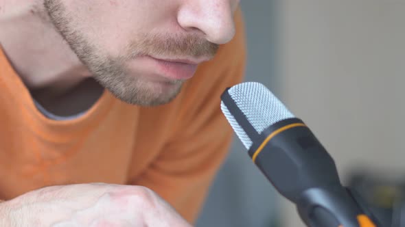 Bearded man making ASMR sounds with microphone eating chips.