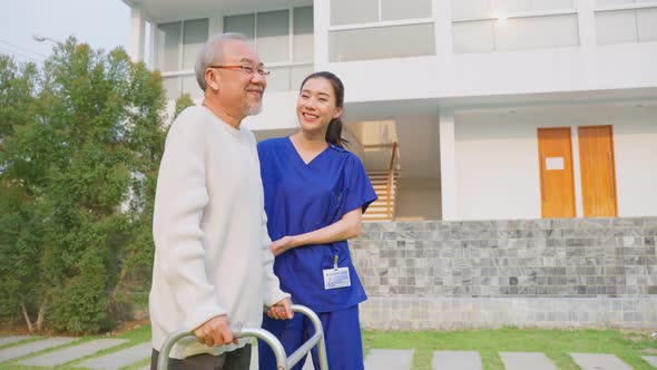 Portrait of Asian caregiver nurse support senior male walking outdoors.