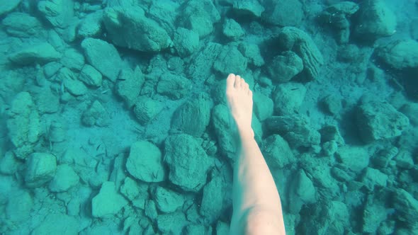 POV Slow Motion Underwater Shot of Woman Swimming in Clear Blue Water.