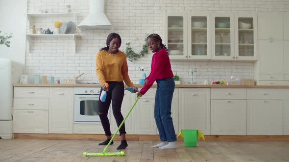 Joyful Teenage Girls Dancing with Cleaning Supplies During Cleanup