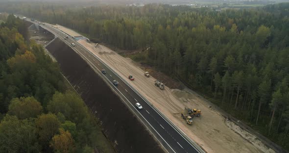 Road Construction Between Green Forest Aerial View at Sunrise